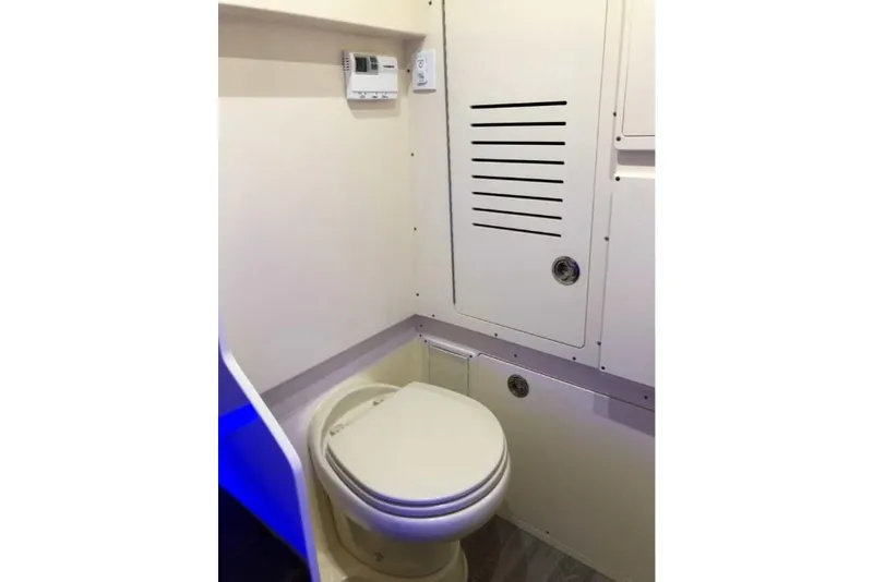 Slide: The Image of 2023 Scout 330 LXF boat interior bathroom with toilet and control panel. - 31