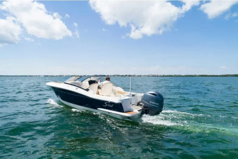 Slide: The Image of 2023 Scout 215 Dorado boat cruising on open water under a clear sky. - 2