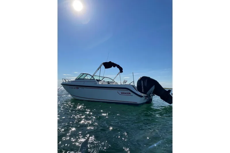 Slide: The Image of 2005 Boston Whaler VENTURA 210 boat on water under clear blue sky. - 11