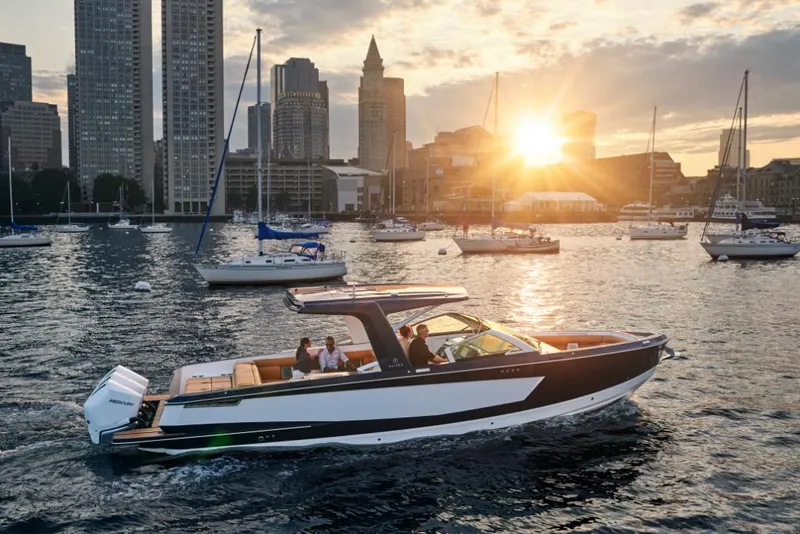 Slide: The Image of 2023 Aviara AV36 boat cruising in a city harbor at sunset with skyscrapers in the background. - 0