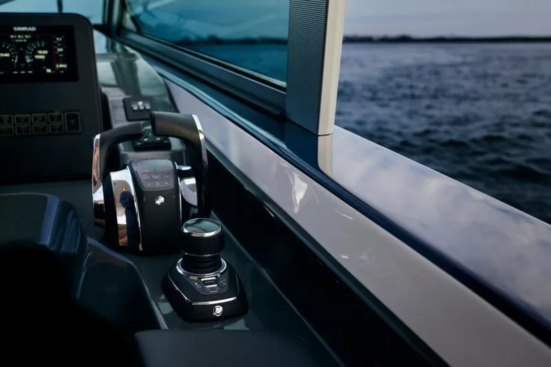 Slide: The Image of 2023 Aviara AV36 boat control panel with throttle and joystick near water. - 11