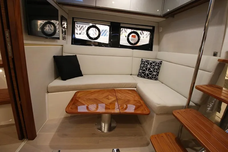 Slide: The Image of 2023 Boston Whaler 405 Conquest interior lounge with wooden table and cushioned seating. - 20