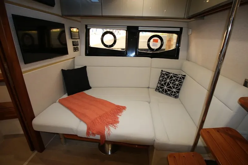 Slide: The Image of 2023 Boston Whaler 405 Conquest interior lounge with white seating, pillows, and a blanket. - 31