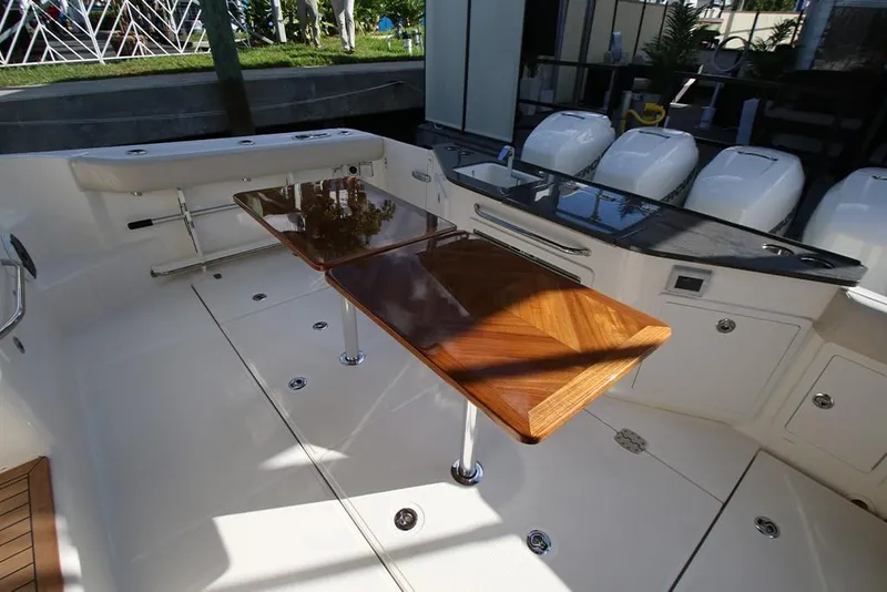 Slide: The Image of 2023 Boston Whaler 405 Conquest boat deck with wooden table and outboard engines. - 34