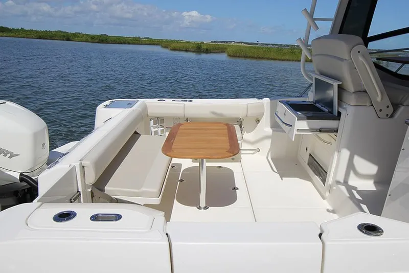 Slide: The Image of 2023 Boston Whaler 325 Conquest boat with spacious deck and wooden table. - 4