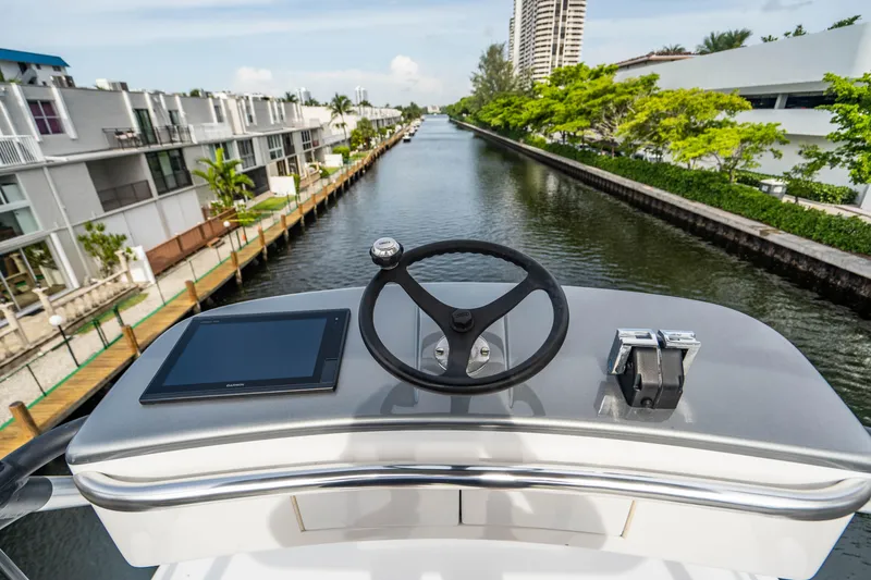 Slide: The Image of Helm of 1999 Jim Smith Custom 66 Sportfish overlooking a canal with modern buildings. - 44