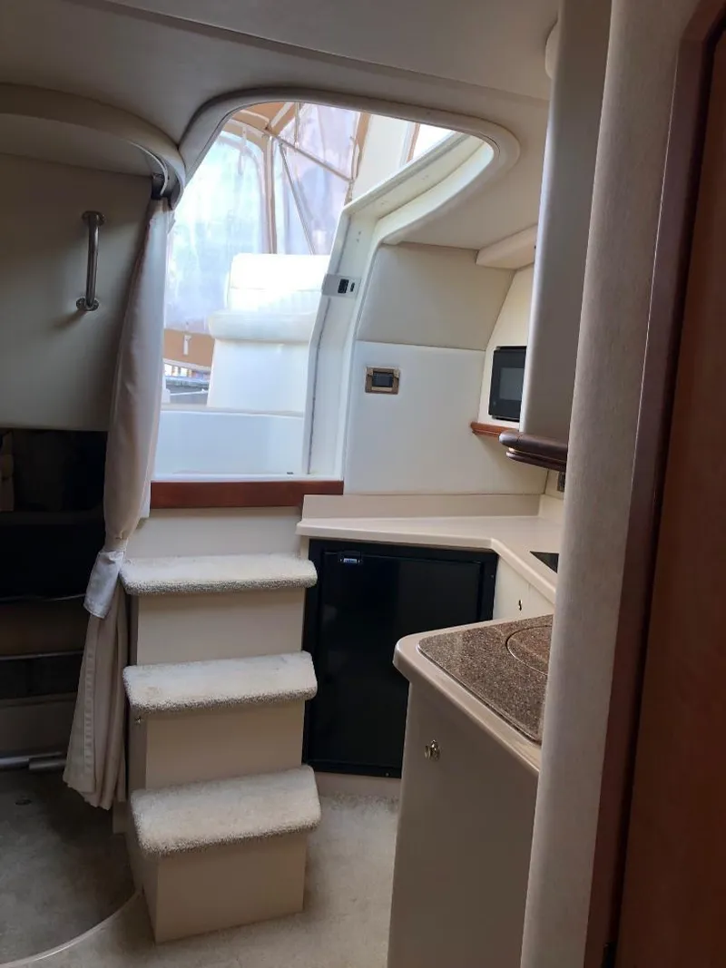 Slide: The Image of 2001 Cruisers Yachts 3470 Express cabin interior with kitchenette and stairs. - 12