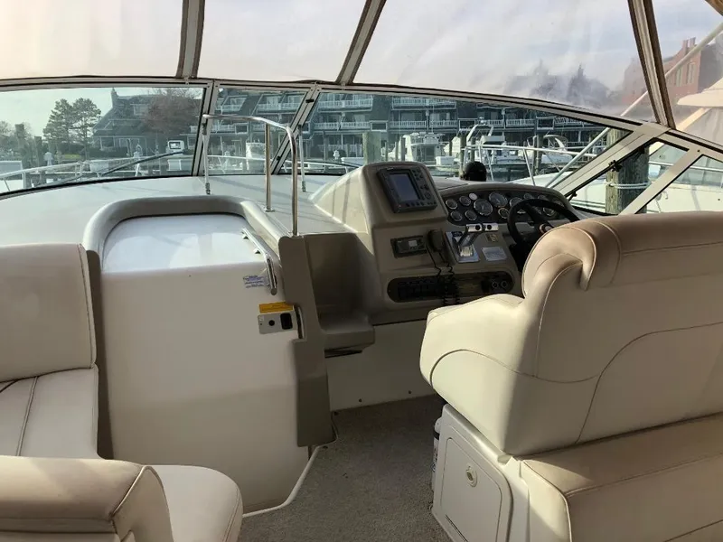 Slide: The Image of 2001 Cruisers Yachts 3470 Express cockpit with helm, beige seating, and marina view. - 9
