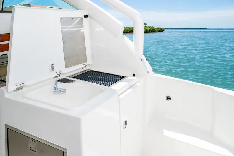 Slide: The Image of 2025 Pursuit DC 326 boat with outdoor sink and grill by the water. - 11