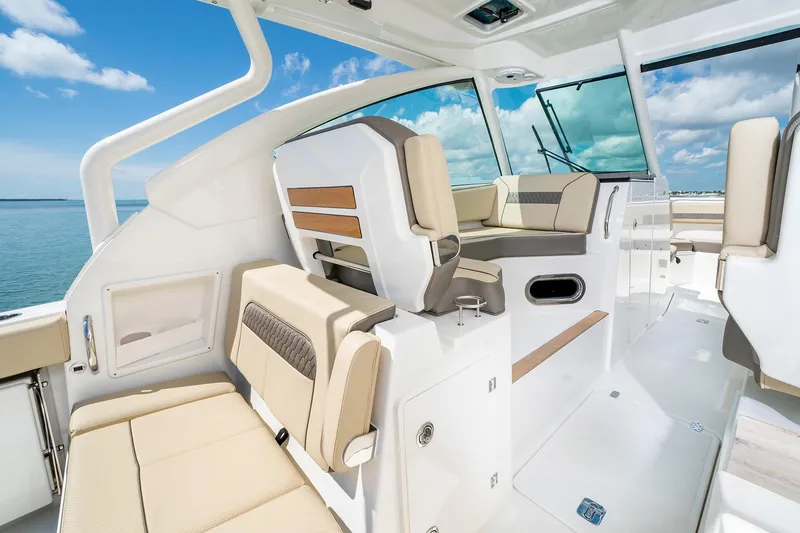 Slide: The Image of 2025 Pursuit DC 326 boat interior with beige seating and ocean view. - 13