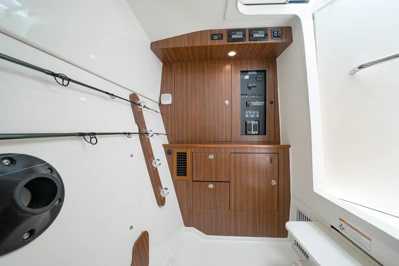 Slide: The Image of Interior cabin of 2025 Pursuit DC 326 boat with wooden paneling and fishing rod holders. - 22