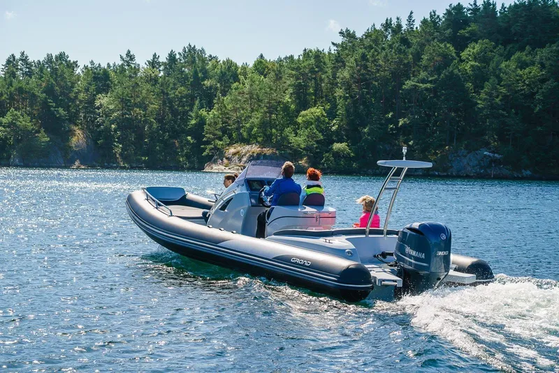 Slide: The Image of 2024 Grand Inflatables G850 boat cruising on a lake with passengers. - 1
