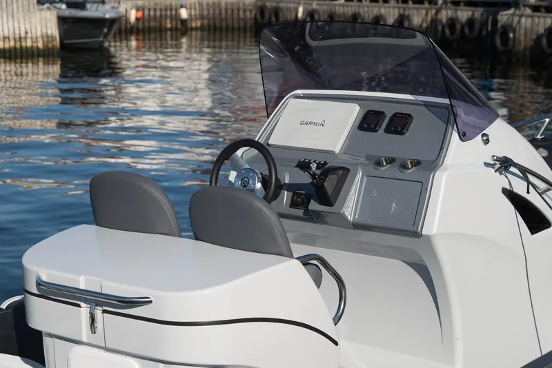Slide: The Image of 2024 Grand Inflatables G850 boat console and seating at a marina. - 11
