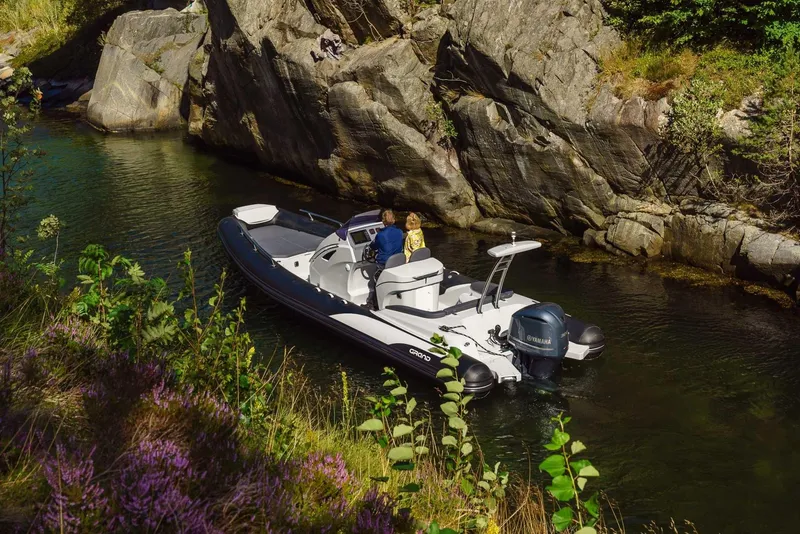 Slide: The Image of 2024 Grand Inflatables G850 boat navigating a narrow rocky waterway surrounded by lush greenery. - 3