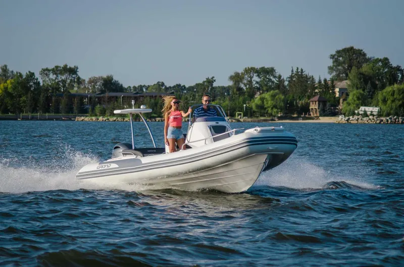 Slide: The Image of 2024 Grand Inflatables G650 boat cruising on a lake with two passengers. - 11