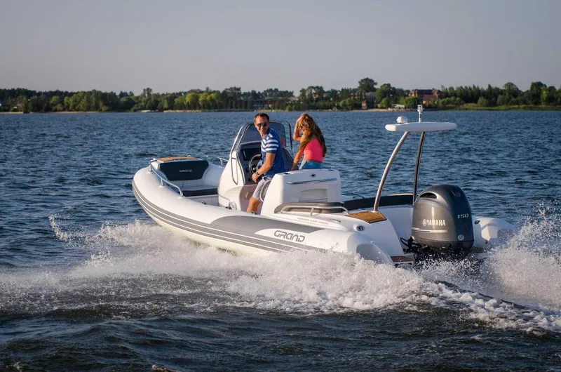 Slide: The Image of 2024 Grand Inflatables G650 boat cruising on a lake with two passengers. - 15