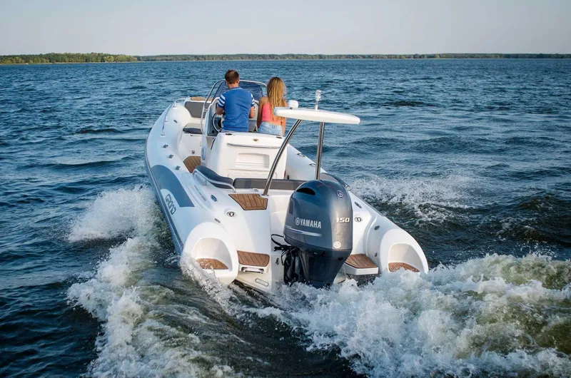 Slide: The Image of 2024 Grand Inflatables G650 boat cruising on a lake with two passengers. - 16