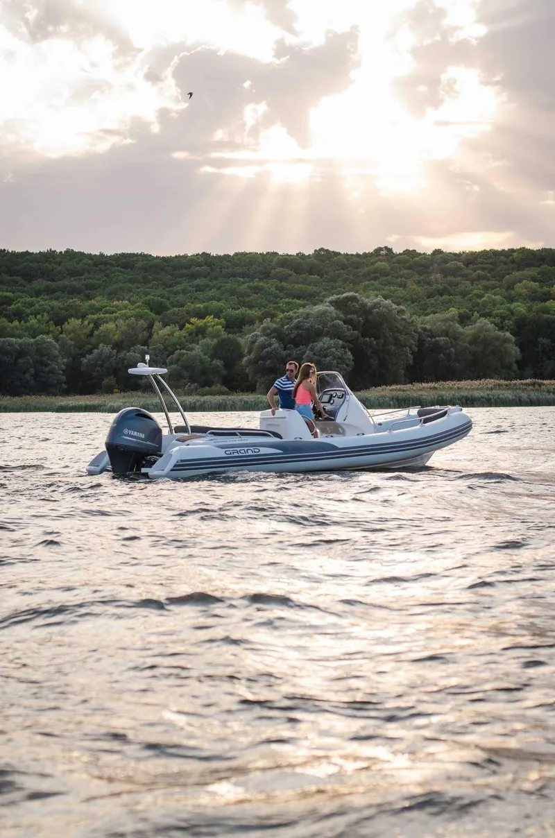 Slide: The Image of 2024 Grand Inflatables G650 boat cruising on a lake at sunset. - 17