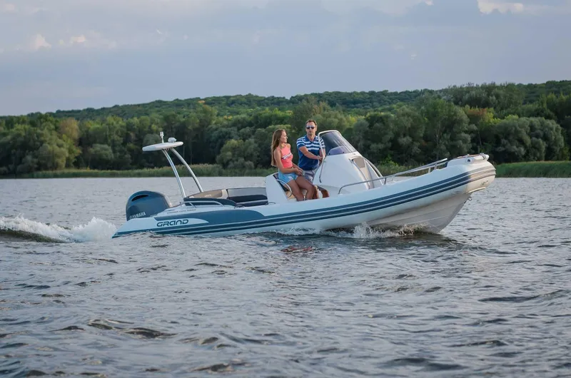 Slide: The Image of 2024 Grand Inflatables G650 boat cruising on a lake with two passengers. - 18
