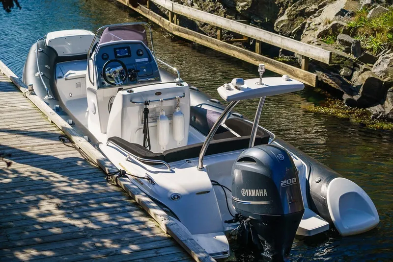 Slide: The Image of 2024 Grand Inflatables G650 boat docked, featuring a Yamaha 200 outboard motor. - 2