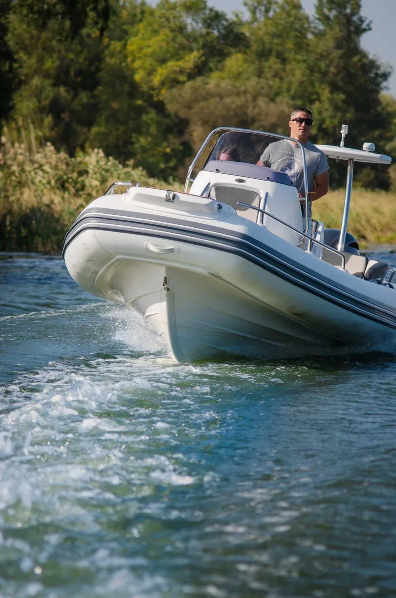 Slide: The Image of 2024 Grand Inflatables G650 boat cruising on a river with a driver. - 24