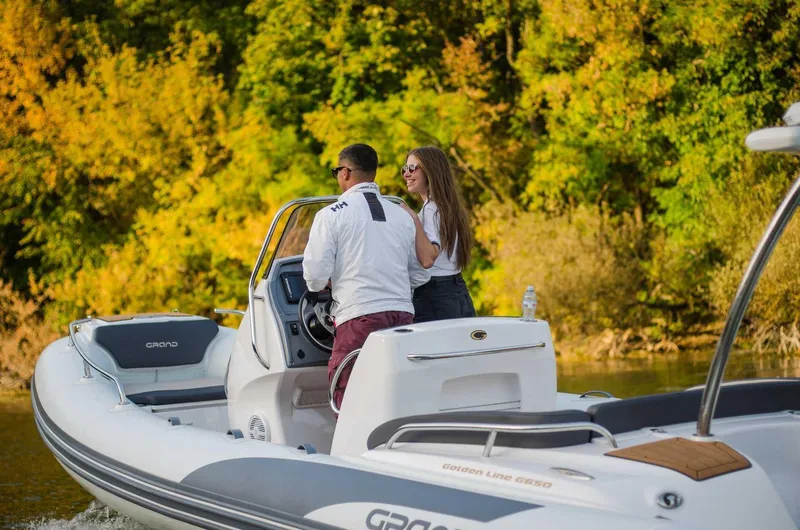 Slide: The Image of 2024 Grand Inflatables G650 boat on a scenic river with two people onboard. - 26