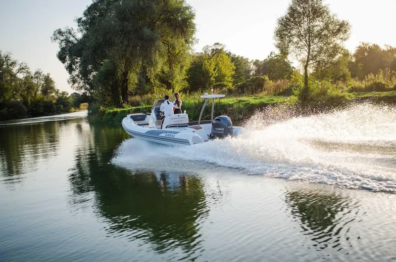 Slide: The Image of 2024 Grand Inflatables G650 boat cruising on a serene river. - 27