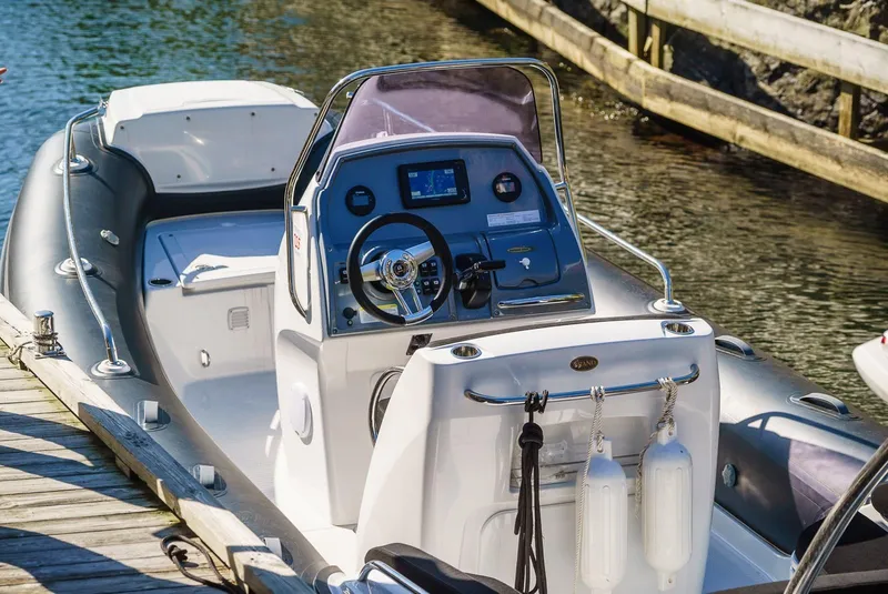 Slide: The Image of 2024 Grand Inflatables G650 boat docked, showcasing steering console and seating. - 3