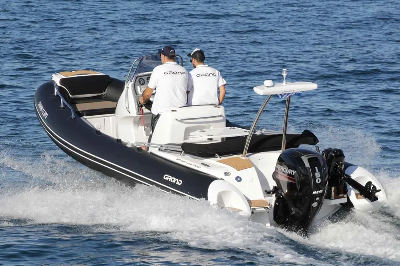 Slide: The Image of 2024 Grand Inflatables G650 boat cruising on water with two people onboard. - 32