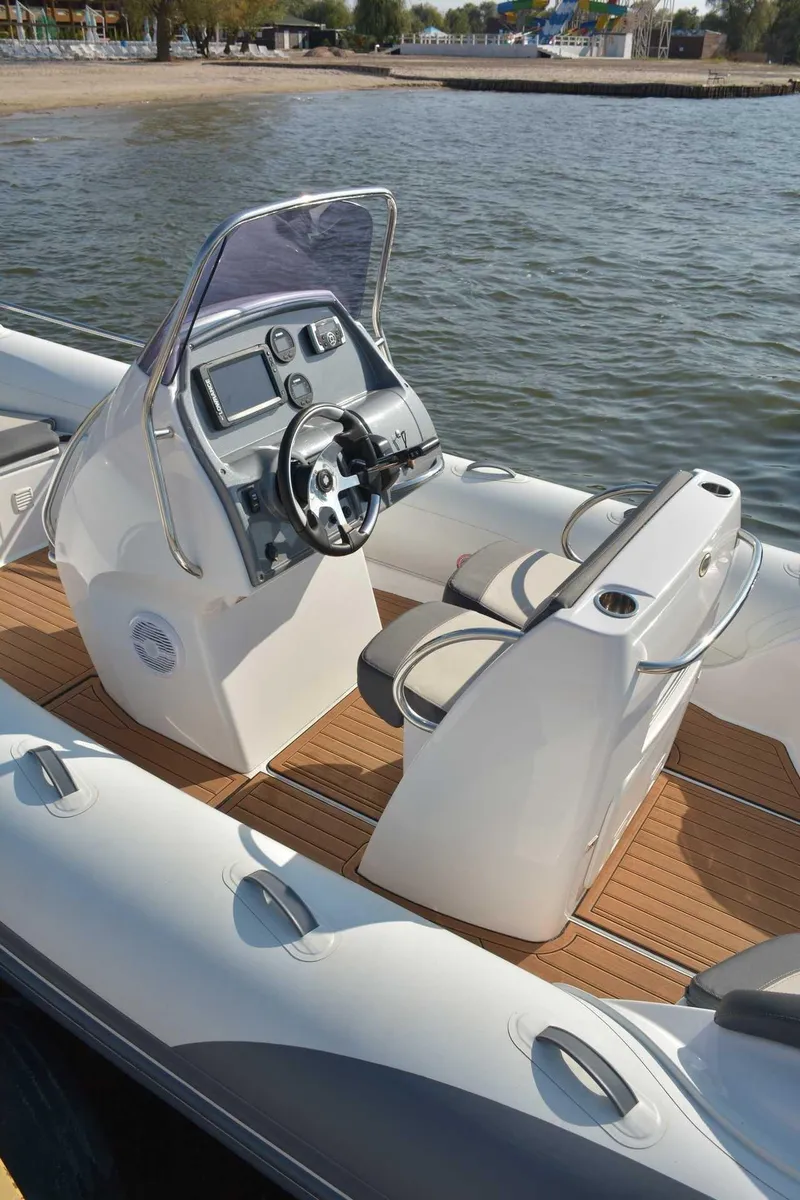 Slide: The Image of 2024 Grand Inflatables G650 boat with modern console and seating, docked by the water. - 7