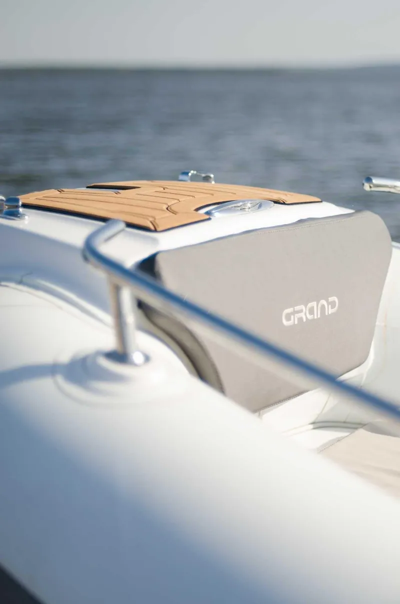 Slide: The Image of 2024 Grand Inflatables G650 boat on water, featuring sleek design and wooden deck. - 9
