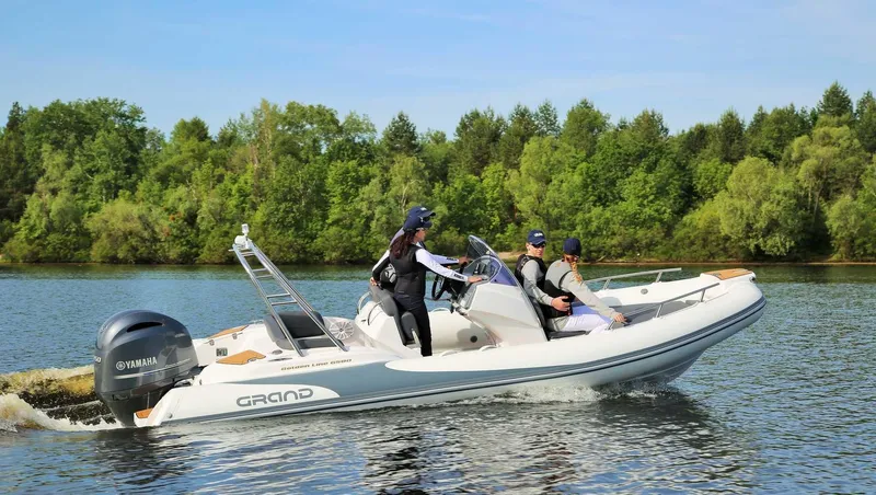 The Image of 2024 Grand Inflatables G580 boat cruising on a lake with passengers. - 1