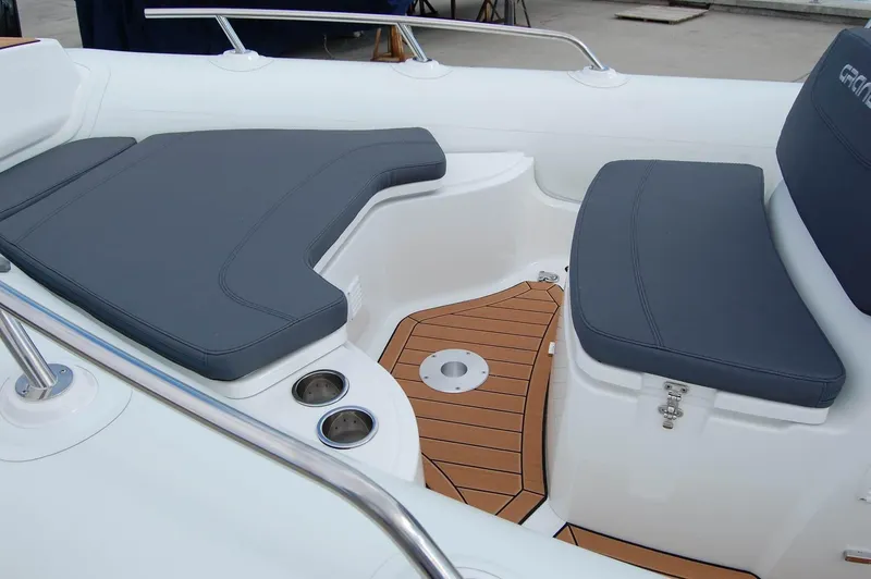 Slide: The Image of 2024 Grand Inflatables G580 boat interior with cushioned seating and teak flooring. - 13