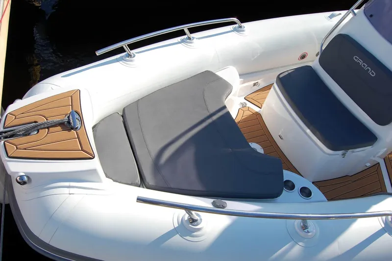 Slide: The Image of 2024 Grand Inflatables G580 boat interior with cushioned seating and teak flooring. - 14