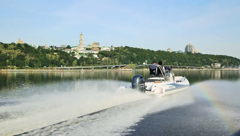 Slide: The Image of 2024 Grand Inflatables G580 boat cruising on a scenic river. - 2