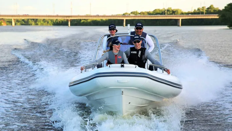 Slide: The Image of 2024 Grand Inflatables G580 boat cruising on a river with four passengers. - 3