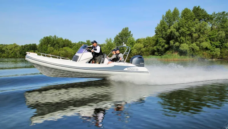 Slide: The Image of 2024 Grand Inflatables G580 speeding on a lake with lush green trees in the background. - 5