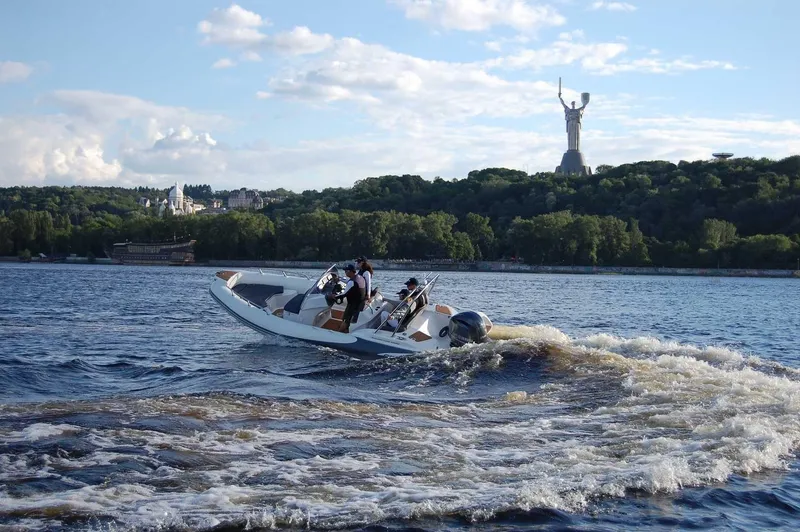Slide: The Image of 2024 Grand Inflatables G580 boat cruising on a river with a statue in the background. - 6