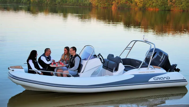 Slide: The Image of 2024 Grand Inflatables G580 boat with people enjoying a calm lake outing. - 8