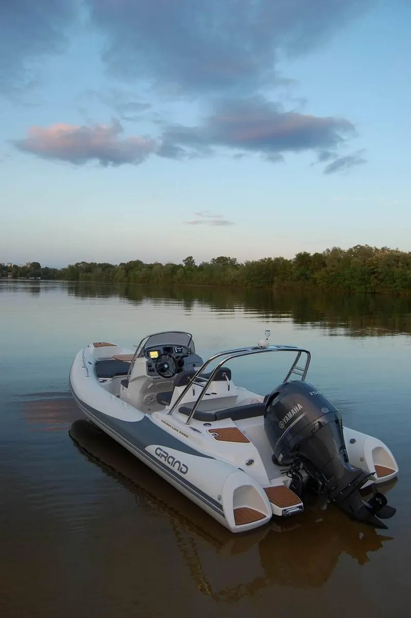 Slide: The Image of 2024 Grand Inflatables G580 boat on calm water at sunset. - 9