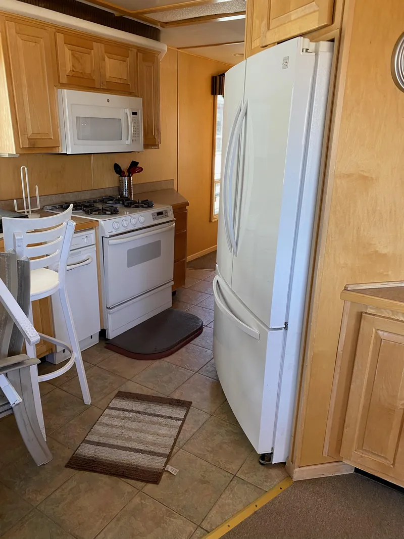 Slide: The Image of 2003 Stardust Cruisers Red Rock Retreat Week 26 kitchen with white appliances and wooden cabinets. - 21