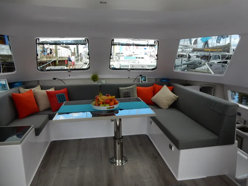 Slide: The Image of 2025 Seawind 1190 Sport interior with modern seating, colorful cushions, and a central table. - 12