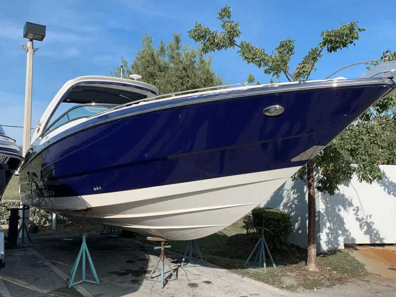 Slide: The Image of 2012 Monterey 328 Super Sport boat on stands, blue and white hull. - 3