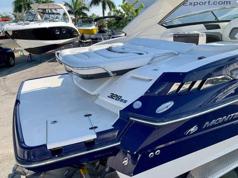 Slide: The Image of 2012 Monterey 328 Super Sport boat with white and blue exterior, docked at a marina. - 5