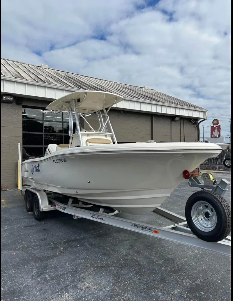 Slide: The Image of 2020 Pioneer 222 Sportfish boat on trailer, parked outside a building under a cloudy sky. - 3