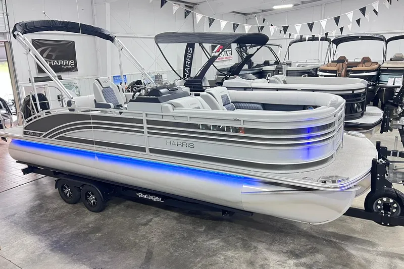 Slide: The Image of 2022 Harris FloteBote SOLTHICE 250 pontoon boat displayed indoors with blue LED lighting. - 2