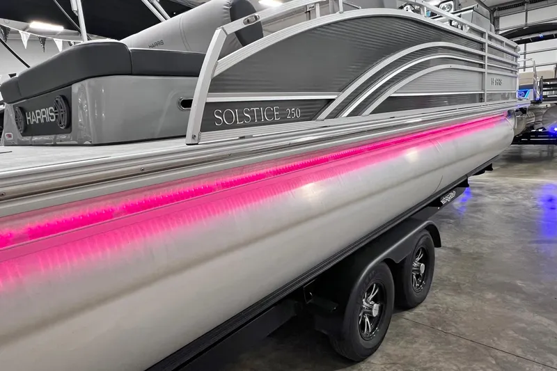 Slide: The Image of 2022 Harris FloteBote SOLSTICE 250 pontoon boat with pink LED lights in a showroom. - 55