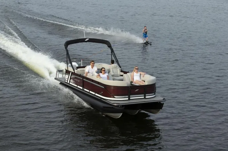 Slide: The Image of 2023 Starcraft SLS 5 pontoon boat towing a water skier on a lake. - 4