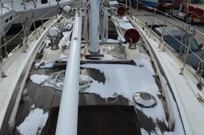 Slide: The Image of 1982 Young Sun Cutter sailboat deck with snow, ropes, and winches in a marina. - 37