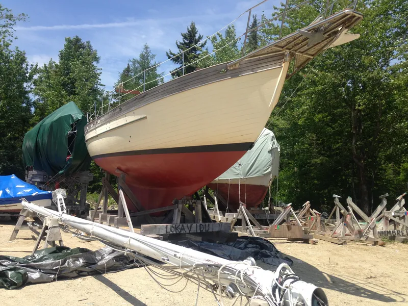 Slide: The Image of 1982 Young Sun Cutter sailboat on dry dock, surrounded by trees and equipment. - 48